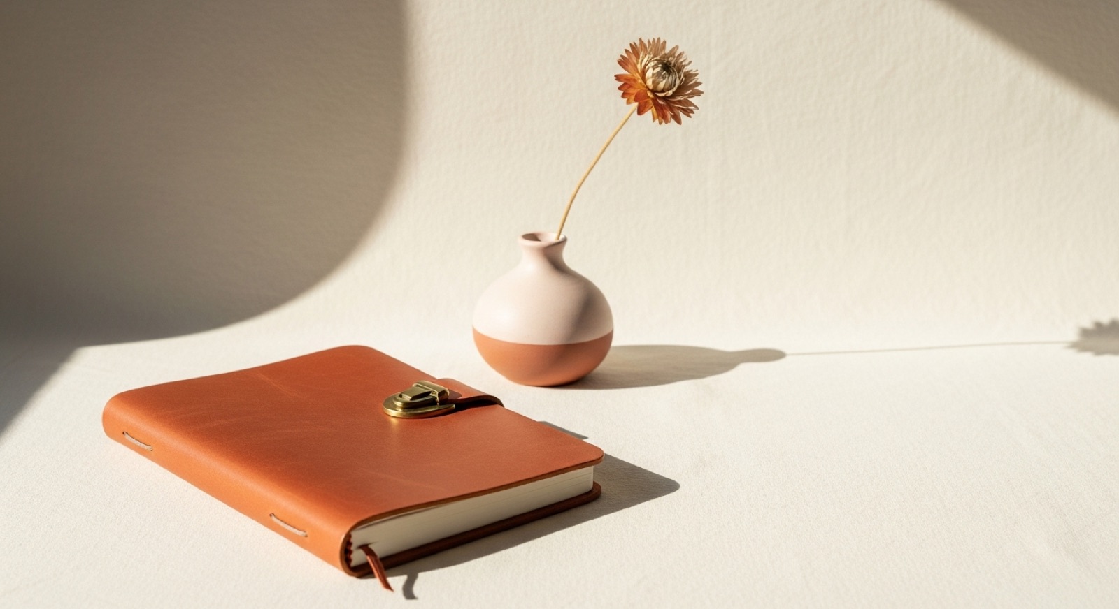 Carnet en cuir terracotta avec un vase épuré, ambiance minimaliste